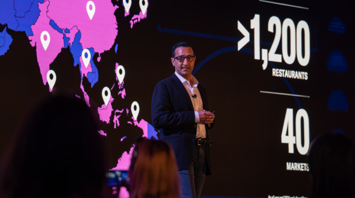 Ankush Tuli speaking on stage in front of a map of Asia