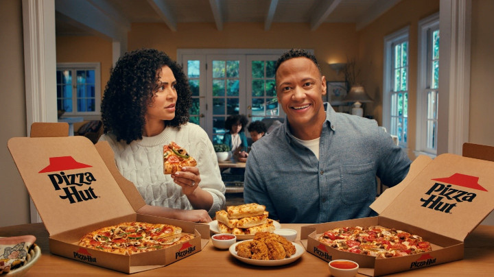 two people with pizza hut boxes and pizza