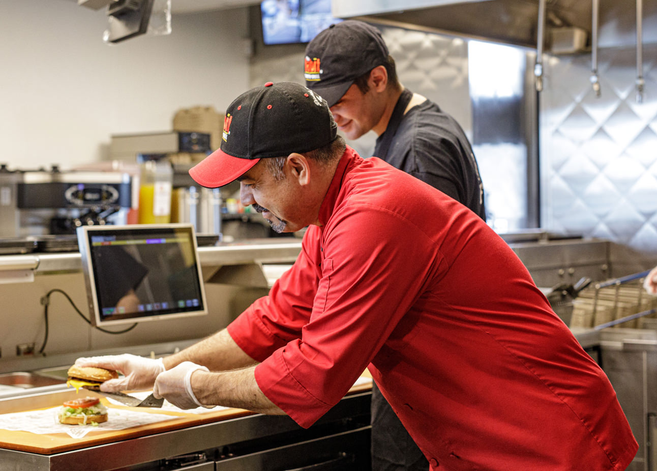 Two Habit Burger Grill prepare an order in the back of a Habit Burger Grill restaurant Two Habit Burger Grill prepare an order in the back of a Habit Burger Grill restaurant